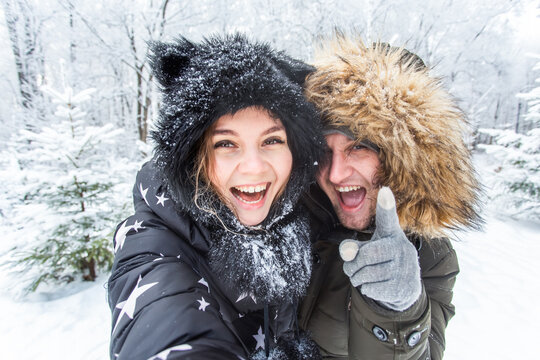 Season, love, technology and leisure concept - happy couple taking selfie by smartphone over winter background