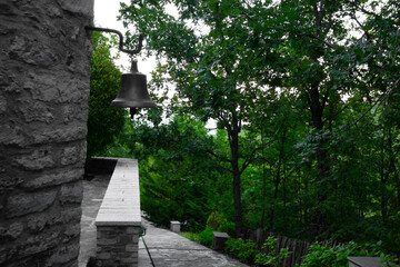 Old church bell at stone wall at the forest