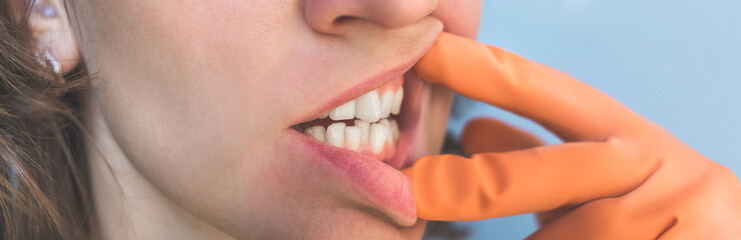 Woman in gloves shows her crooked teeth.
