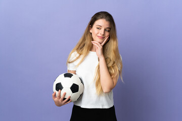 Young blonde football player woman isolated on purple background looking up while smiling