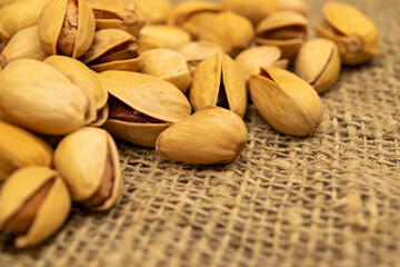 Salted pistachios lie on the burlap. Close up.