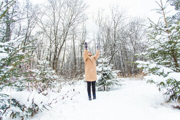 Young woman throwing snow in the air at sunny winter day, she is happy and fun.