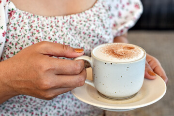 Close-up view, Hot cappuccino coffee in woman hand.
