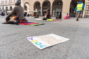 Yoga teachers protesting against the blockade and restrictions of Covid-19 in a square in Brescia, Italy. Colored writing on the sheet of paper: "How can I feel good without yoga?".