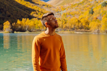 Happy man at the crystal lake in autumnal mountains. Mountain lake and hiker