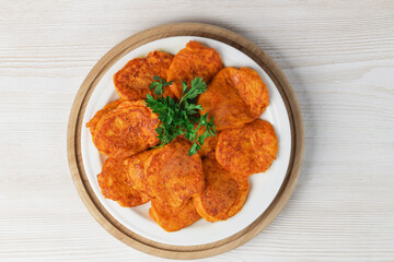 Pumpkin cutlets. Vegetable burgers on a white plate on a light wooden background. Top view.