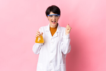 Young scientific woman isolated on pink background celebrating a victory in winner position