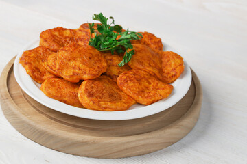 Pumpkin cutlets. Vegetable burgers on a white plate on a light wooden background.