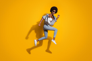 Fototapeta na wymiar Full length photo of sportive young lady wear casual denim outfit jumping running isolated yellow color background