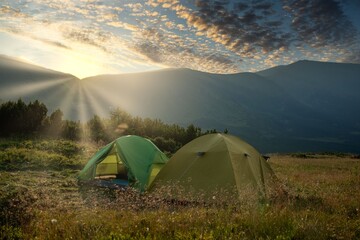 view of tourist tent in mountains at sunrise or sunset. Camping background. Adventure travel active...