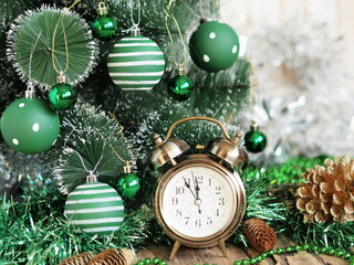 Fototapeta na wymiar Greeting card for Christmas and New Year. Retro alarm clock on the eve of Christmas near a decorative tree, dressed up in green style.
