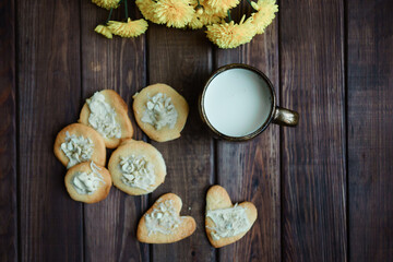 Fototapeta na wymiar homemade cookies in nuts and a cup of milk on a wooden background. Valentine's Day. romantic atmosphere