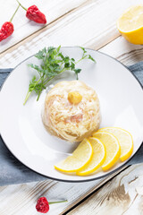 jelly on a plate with lemon slices, parsley and mustard. Chili pepper is on the table.