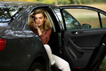 Stylish woman sitting in a grey car in decoration