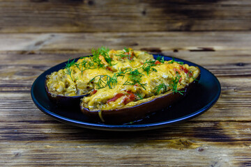 Plate with baked stuffed eggplants on a wooden table