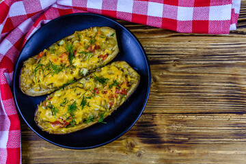 Plate with baked stuffed eggplants on a wooden table. Top view