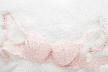 Light pink bra on white fluffy fur blanket background. Daily underwear. Closeup. Empty place for...