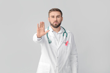 Doctor with pink ribbon on grey background. Breast cancer awareness concept