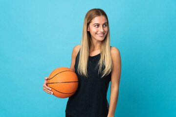 Young woman playing basketball  isolated on white background looking to the side and smiling