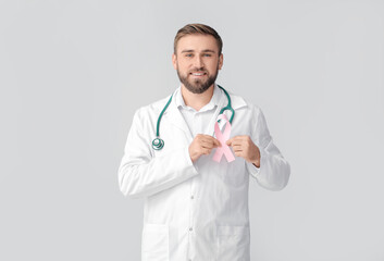 Doctor with pink ribbon on grey background. Breast cancer awareness concept