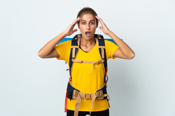 Young mountaineer woman with a big backpack isolated on white background with surprise expression