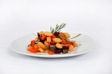 Vegetable salad with boiled beans, carrots, beets and pickled cucumbers isolated on a white background.