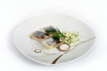 Salted herring slices with onion, dill and spices on  plate isolated on a white background.