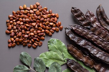 Between leaves and pods, a handful of carob seeds