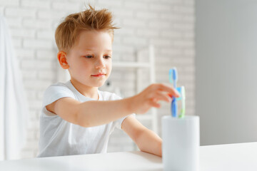 Little boy reaching out for toothbrush in bathroom