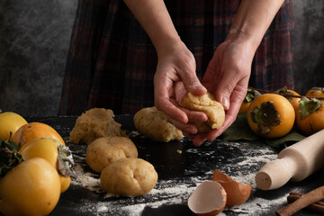 Close up of woman hands preparing autumn sweet pie with raw persimmons