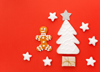Fototapeta na wymiar A gingerbread man is located on a red background along with gifts and a Christmas tree. Christmas New Year concept. There is a place for text