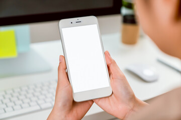 Hand holding smartphone mockup of blank screen on the table. Take your screen to put on advertising.