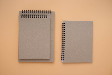 Top view above of Three school book brown closed spiral blank paper cover notebook isolated on brown background for design a mockup. Education and business concept. flat lay