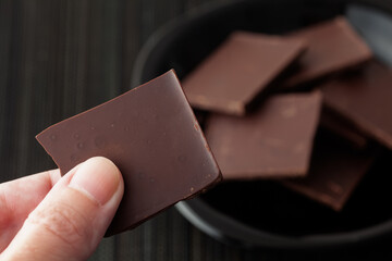 Man holding a piece of broken dark chocolate