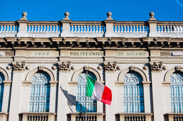 Upper part of the facade of the Milan Polytechnic building with italian flag