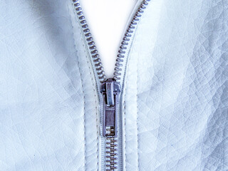 Black metal zipper on a white leather jacket close-up.