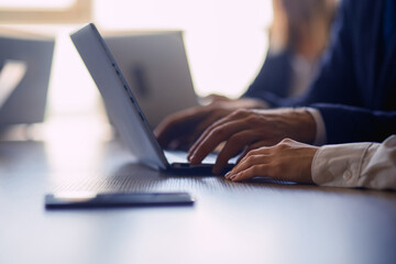 Business people working on laptop computer. Close up of human hands. Selective focus on female arm. Cohesive work in the office.