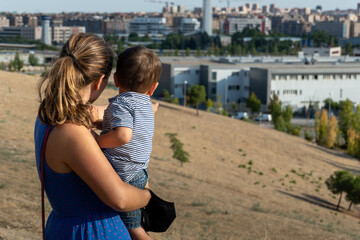 Fototapeta na wymiar Mother and child playing in the country with the city in the background