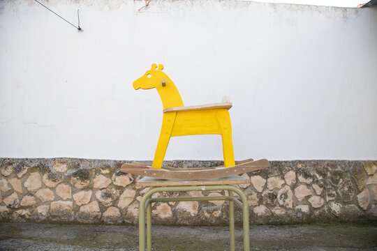 man painting homemade giraffe-shaped rocking horse