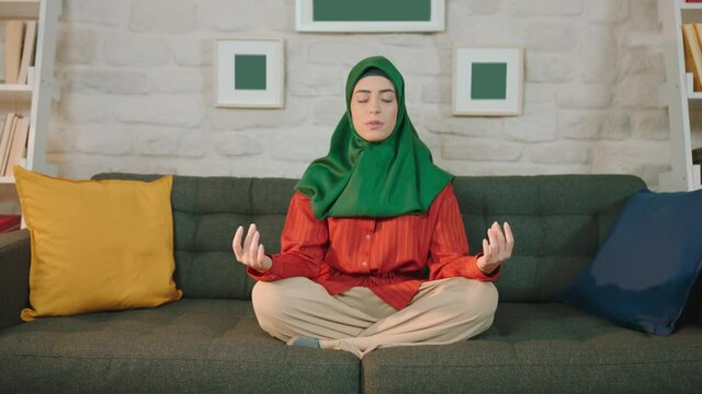 Muslim woman wearing a hijab is practicing yoga at home. Meditation.Bound angle pose. Baddha Konasana