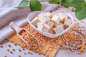 Tofu, also known as bean curd, diced in a faience white bowl in the form of heart on a bamboo...