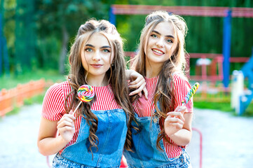 Beautiful teenage twins sisters with colorful lollipops