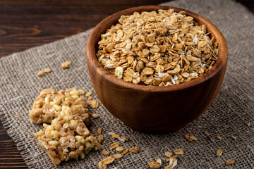 Granola and granola bar on dark wooden background.
