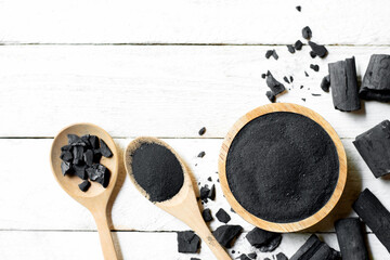 The crushed wood charcoal is placed in a cup placed on a white wooden table.