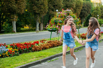 Obraz premium girls twins run on the background of attractions, emotions of happiness and joy, youth