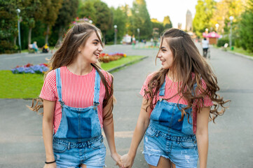 girls twins run on the background of attractions, emotions of happiness and joy, youth