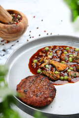 venison meat pattie with peas pepper and ingredients on light background