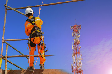 Worker on the high scaffolding wear equipment protective full safety harness on structure site project background.