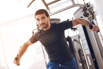 A man is doing strength exercises on a modern gym.
