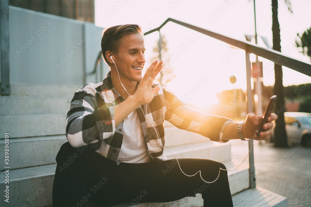 Poster smiling caucasian man traveler using roaming connection sitting on city square making video call dur